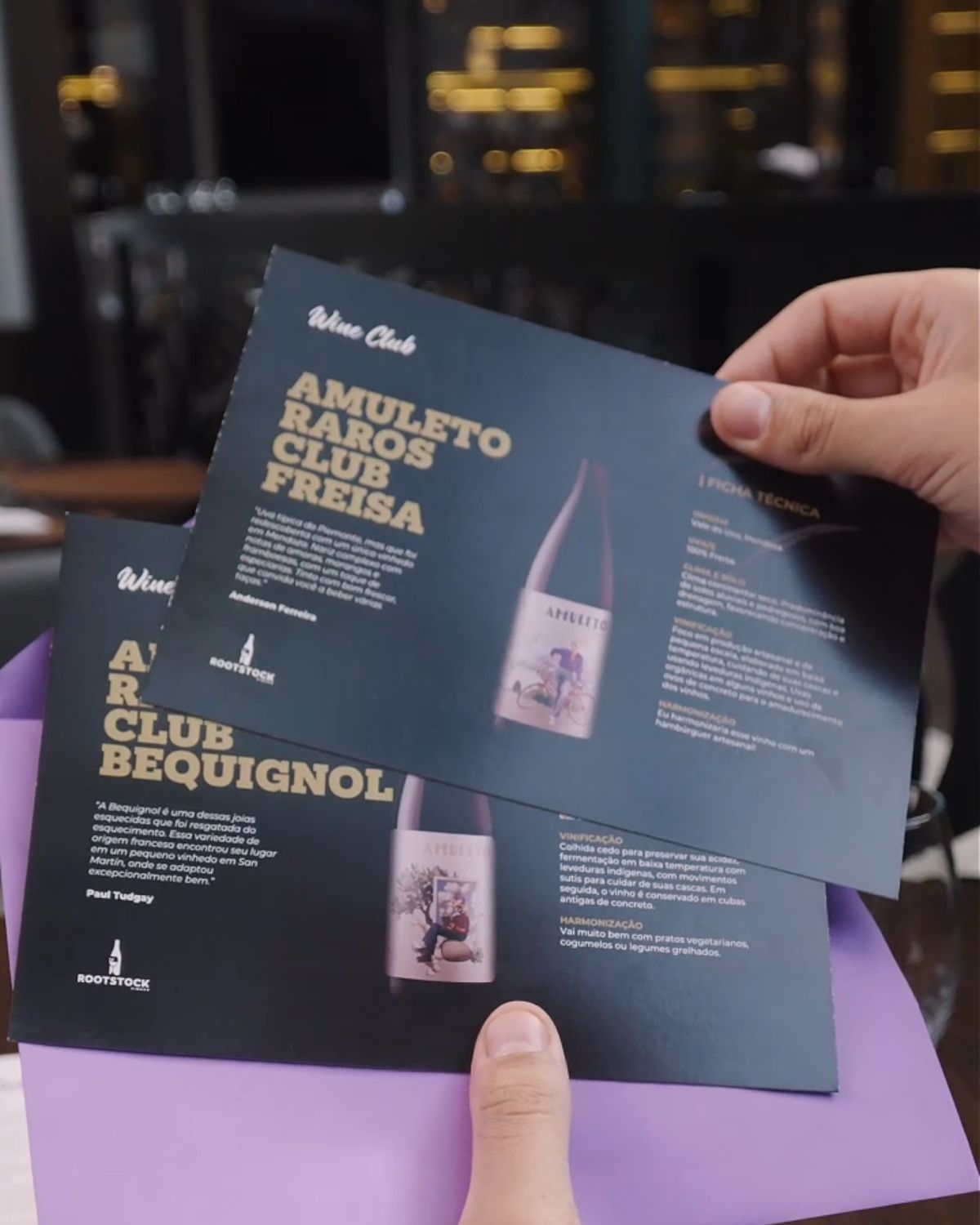 Fichas dos vinhos do mês saindo do envelope lilás do clube